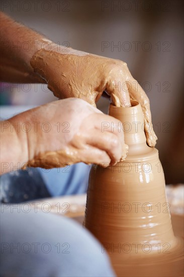 Hands working with clay on potter's wheel