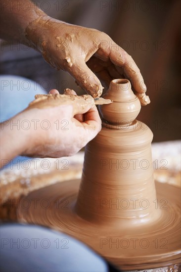 Hands working with clay on potter's wheel