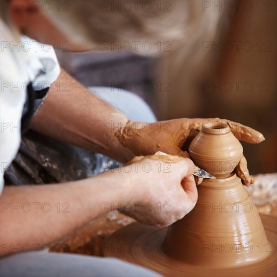 Hands working with clay on potter's wheel