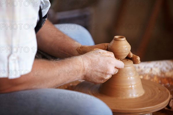 Hands working with clay on potter's wheel