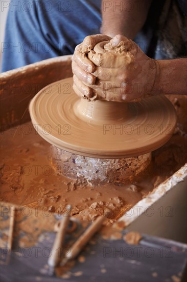 Hands working with clay on potter's wheel