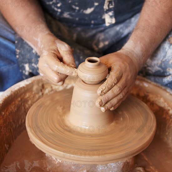 Elevated view of hands working with clay on potter's wheel