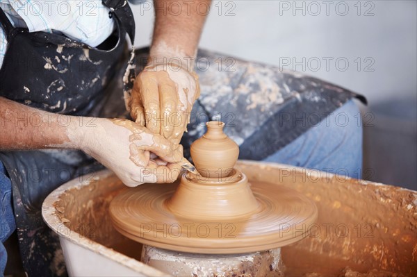 Hands working with clay on potter's wheel