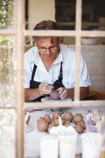 Portrait of mature man decorating small vase