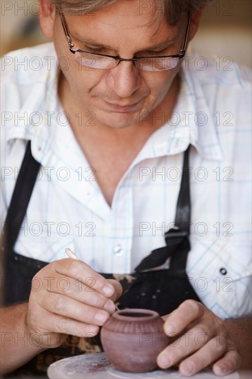 Portrait of male potter carving small vase