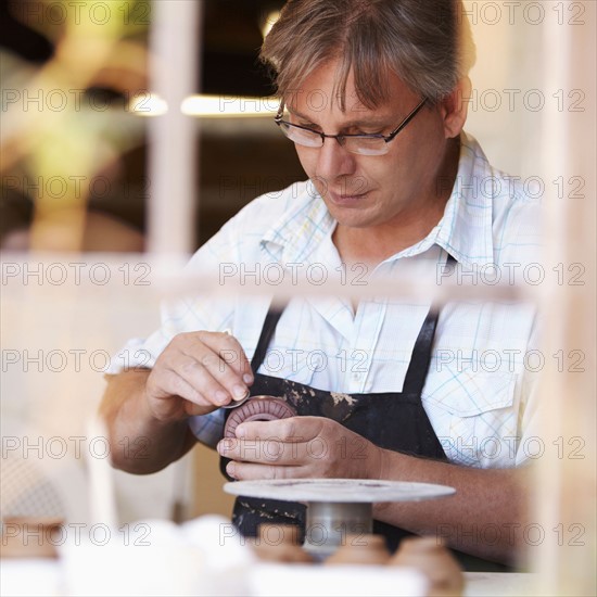 Portrait of mature man decorating clay vase