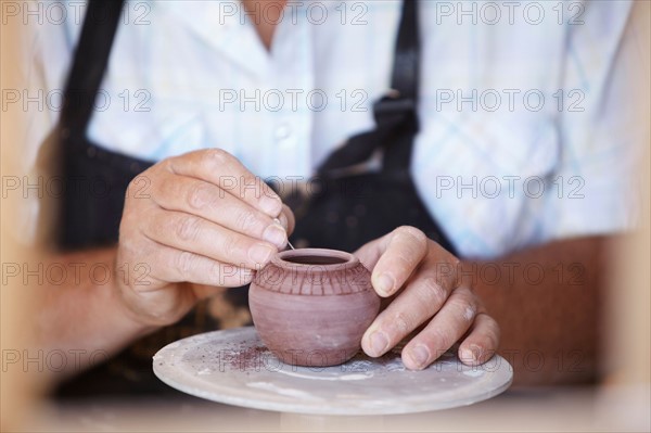 Close-up of male potter holding small vase, carving