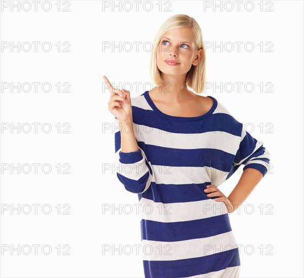 Studio portrait of young woman pointing