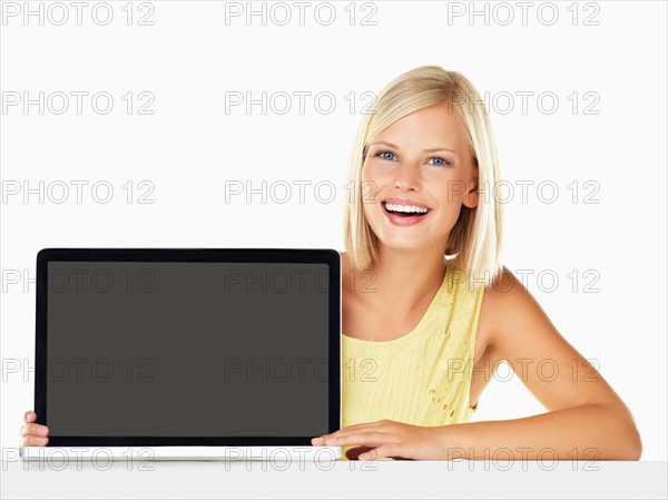 Studio portrait of young woman holding new laptop