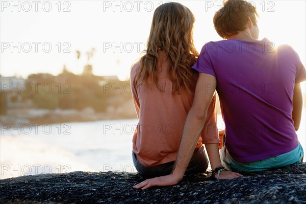 Rear view of young couple sitting at beach