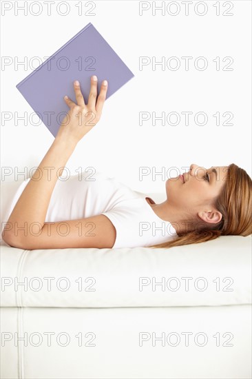 Young woman lying on bed and reading