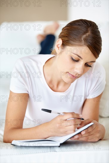 Young woman lying on bed and reading