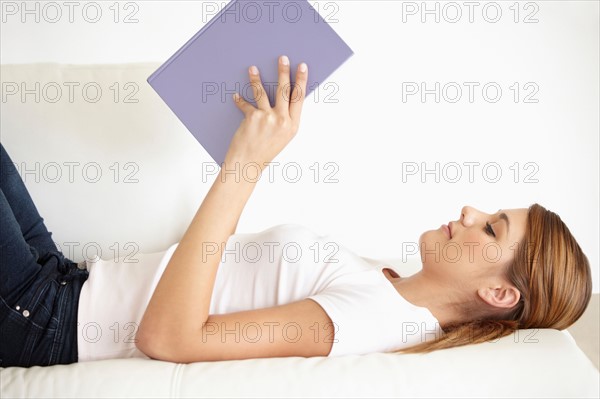 Young woman lying on bed and reading
