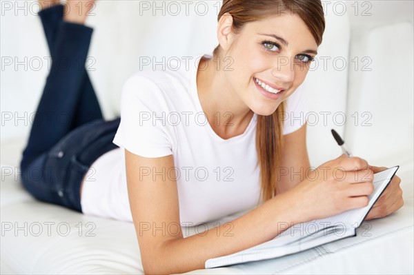 Portrait of young woman writing in notepad