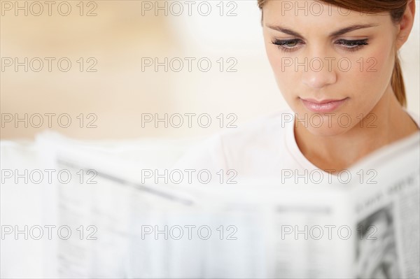 Young woman reading newspaper