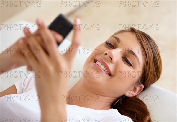 Young woman lying on bed and using cell phone
