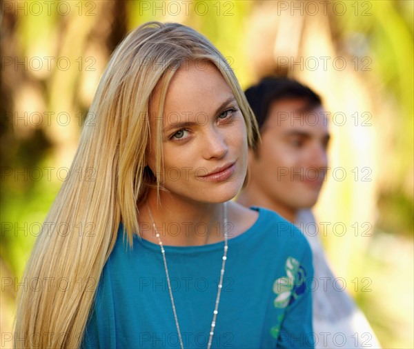 Portrait of young woman, man in background