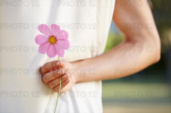 Man holding flower behind back