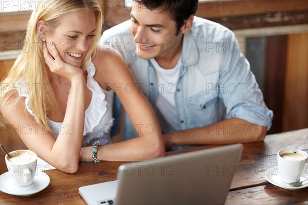 Couple using laptop in cafe