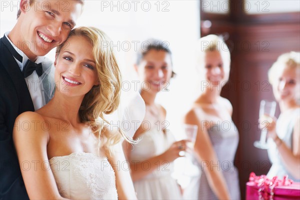 Portrait of newly wed couple, bridesmaids in background