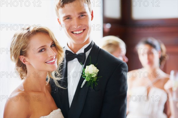 Portrait of newly wed couple, bridesmaids in background