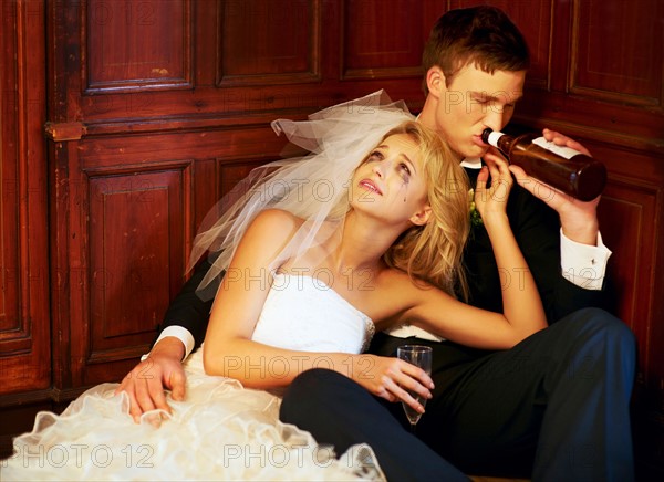 Drunk bride and groom sitting on floor