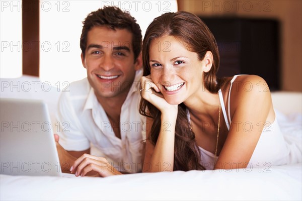 Couple using laptop while lying in bed