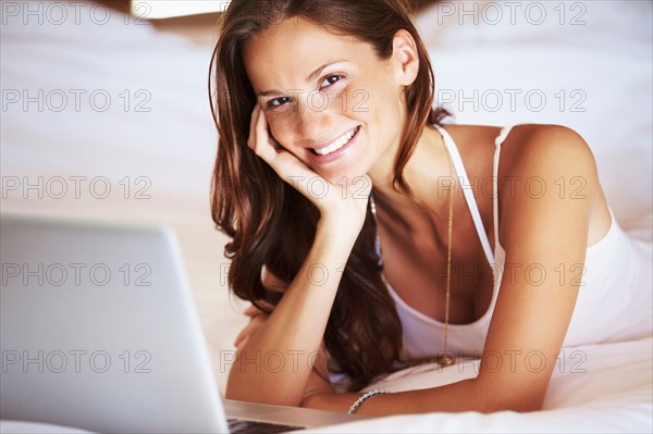 Woman using laptop while lying in bed