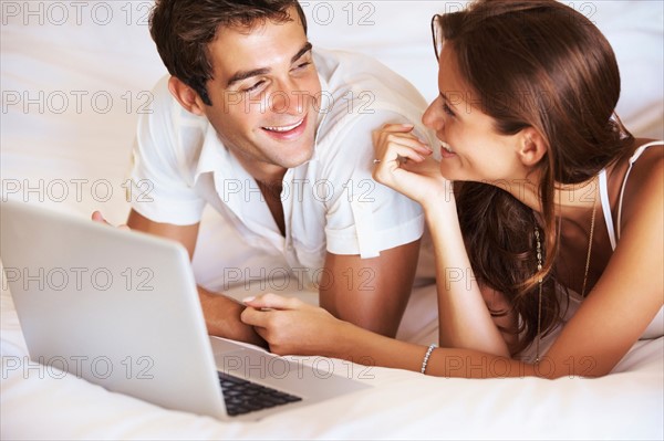 Couple using laptop while lying in bed