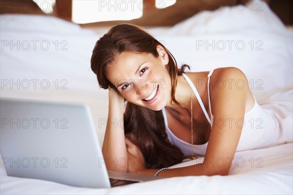 Woman using laptop while lying in bed