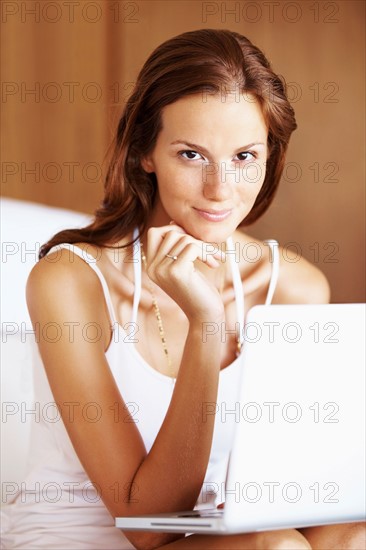 Woman using laptop while sitting on bed