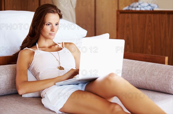 Woman using laptop while sitting on bed