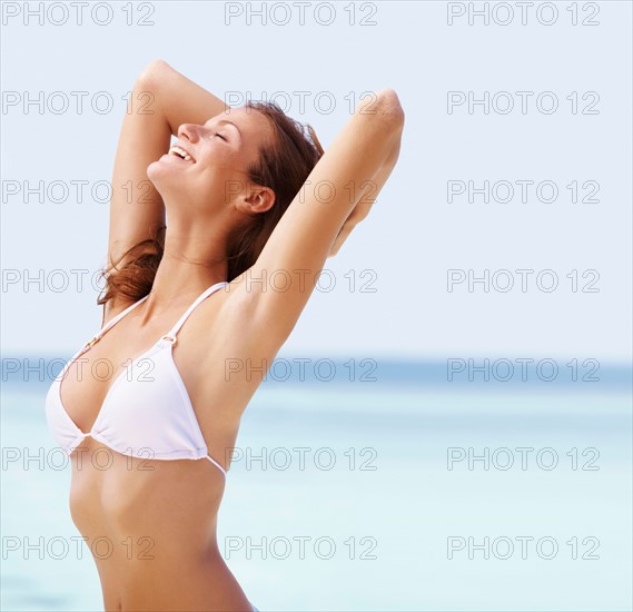 Portrait of young woman in bikini, hands behind head