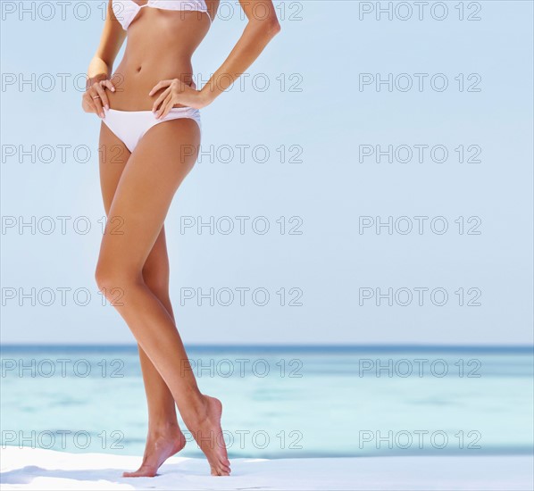 Young woman wearing bikini, low section