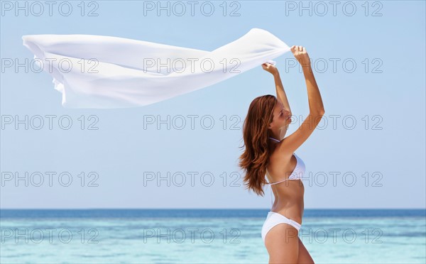 Portrait of young woman in bikini, arms raised