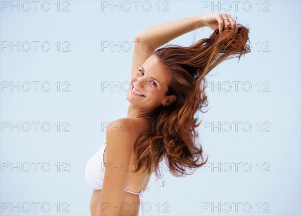 Portrait of young woman in bikini with hand in hair