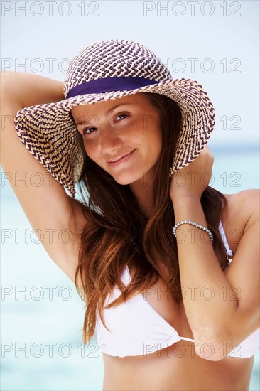 Portrait of young woman in bikini and straw hat