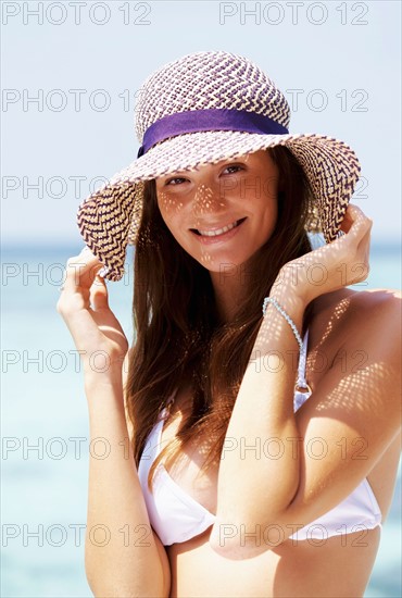 Portrait of young woman in bikini and straw hat