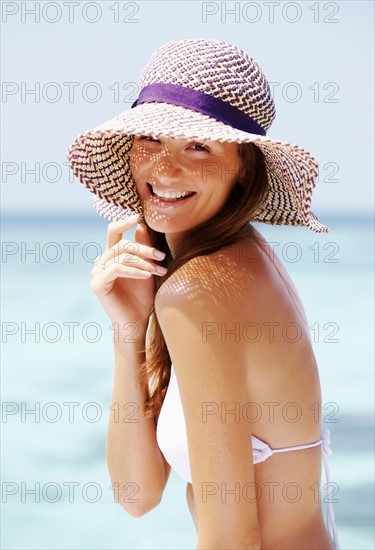 Portrait of young woman in bikini and straw hat