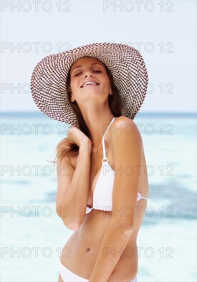 Portrait of young woman in bikini and straw hat