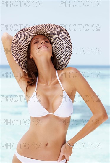 Portrait of young woman in bikini and straw hat