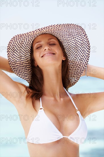 Portrait of young woman in bikini and straw hat