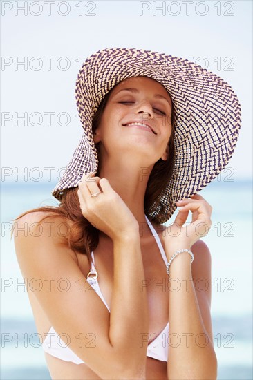 Portrait of young woman in bikini and straw hat