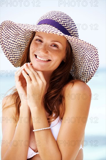 Portrait of young woman in bikini and straw hat