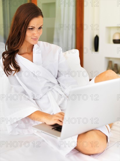 Woman using laptop while sitting on bed