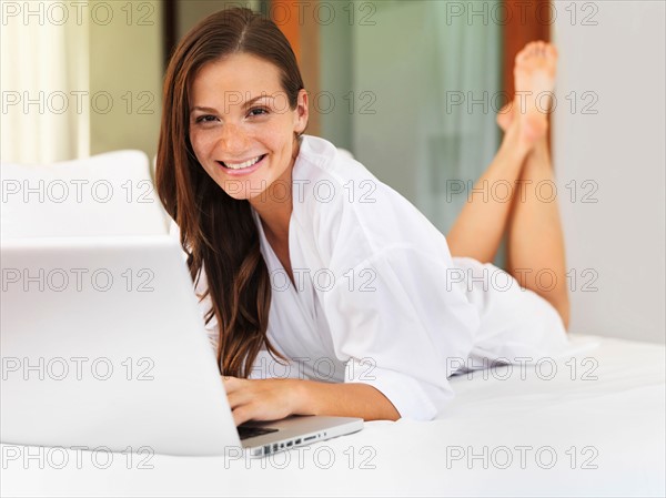 Woman using laptop while lying on bed