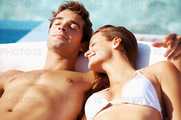 Couple sunbathing at swimming pool