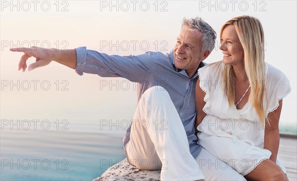 Mature couple sitting by seashore