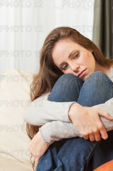 Sad woman sitting on sofa and looking away