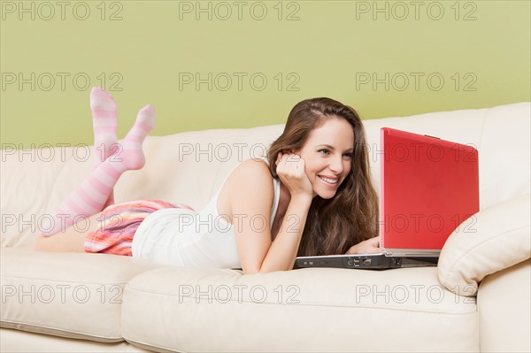 Woman lying on sofa with laptop